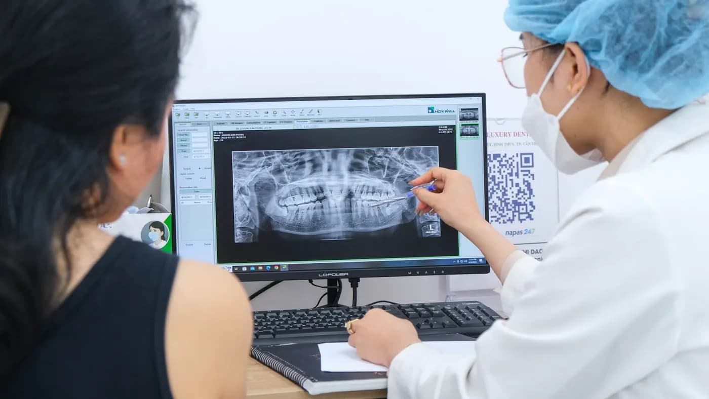 A dentist explaining a full-mouth X-ray on screen
