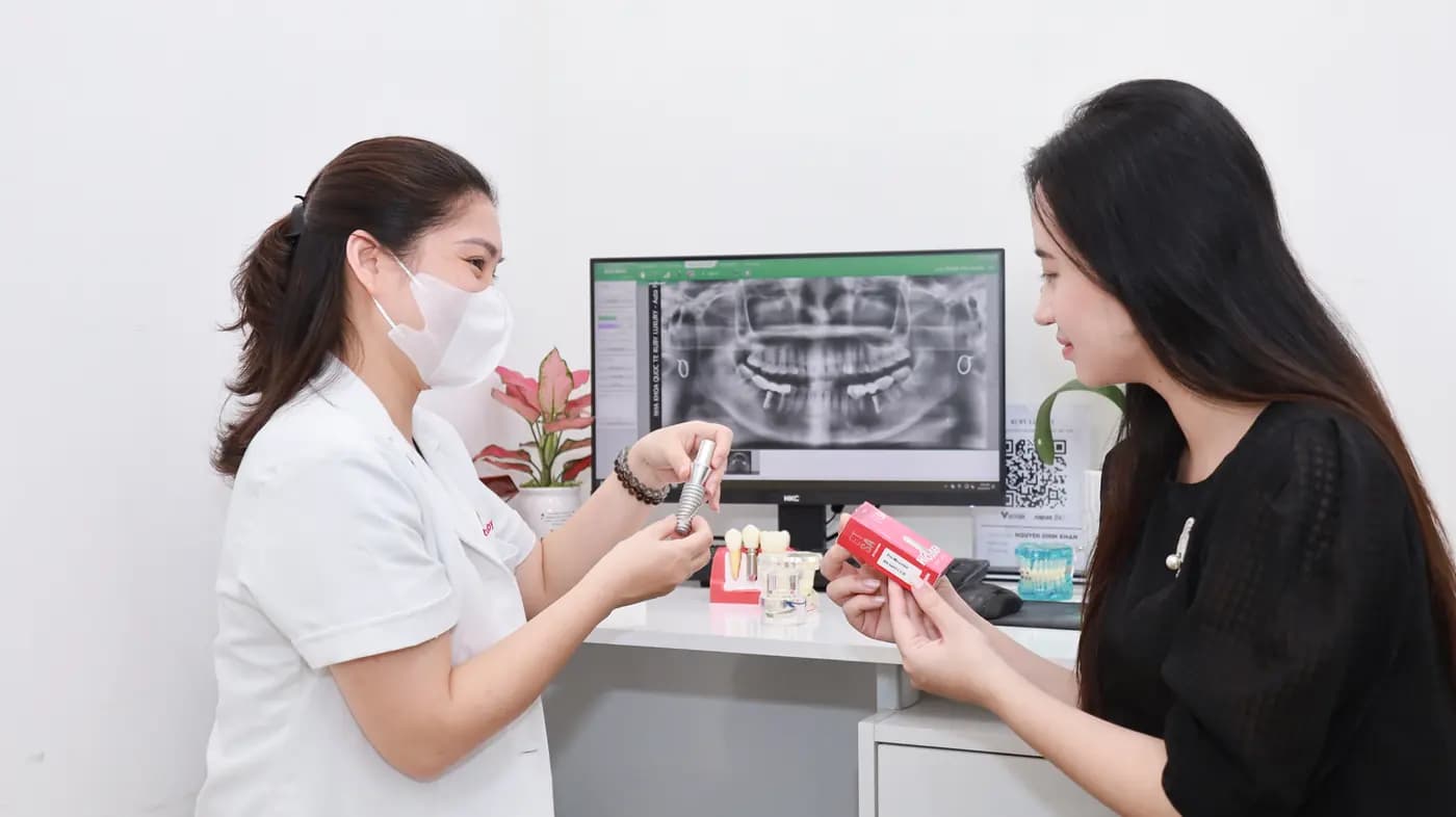 A dentist holding a tooth model and explaining a full-mouth X-ray to a patient